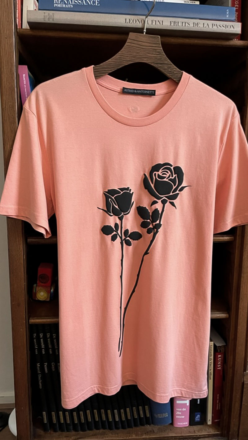Picture of the front view of organic cotton soft orange T-shirt "Feeling Rosie" printed with two large puffy black roses on the front of the shirt with stems running till the end.