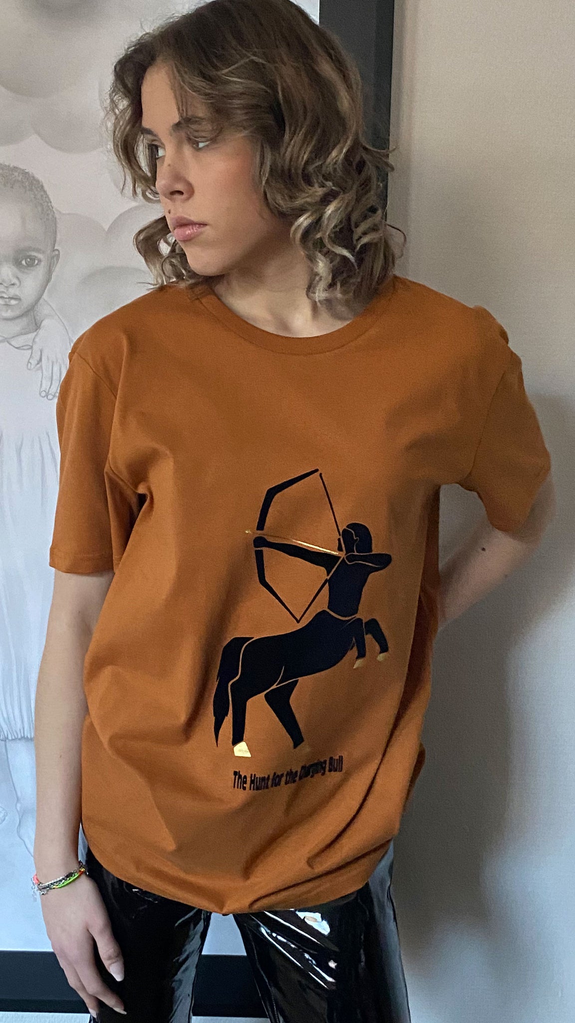 Vegan Approved, saffron yellow/orange heist T-shirt “The Hunt for the Charging Bull” is a metaphor for hunting down the extreme forms of Capitalism existing nowadays. By Atelier Astrid & Antoinette