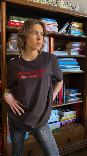 T-Shirt with text saying: "Not black, not white, not yellow or blue, my blood is red and yours is too." by Atelier Astrid & Antoinette 